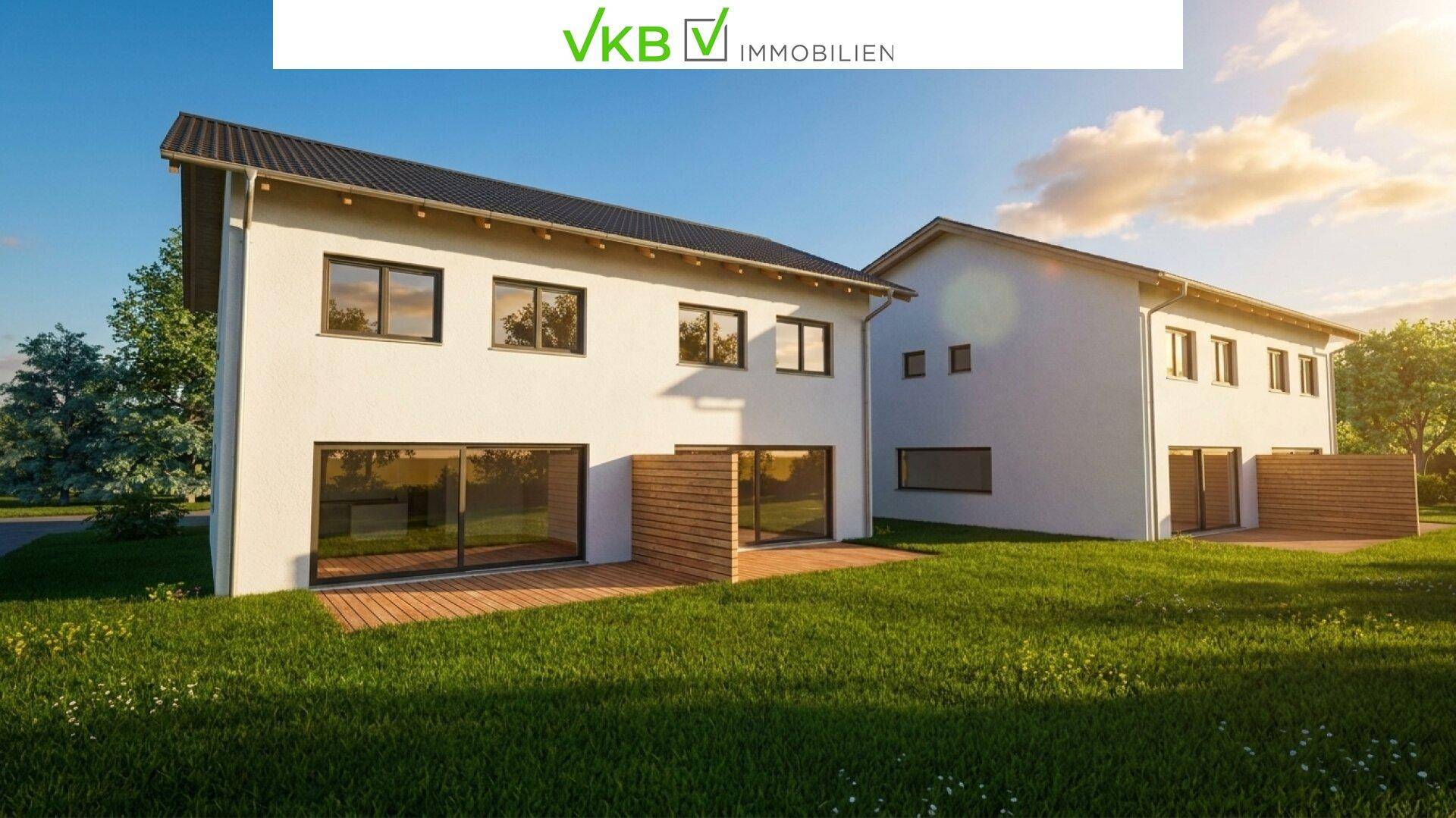 Moderne weiße Doppelhaushälften mit großen Fenstern, Holzterrassen und grünem Garten unter sonnigem Himmel.