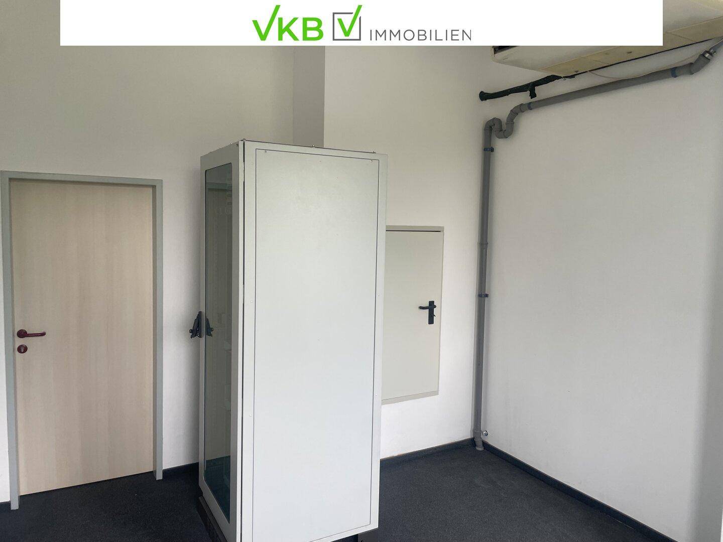 Einfacher Abstellraum mit zwei Türen, einem Schrank und sichtbaren Rohren an der Decke.