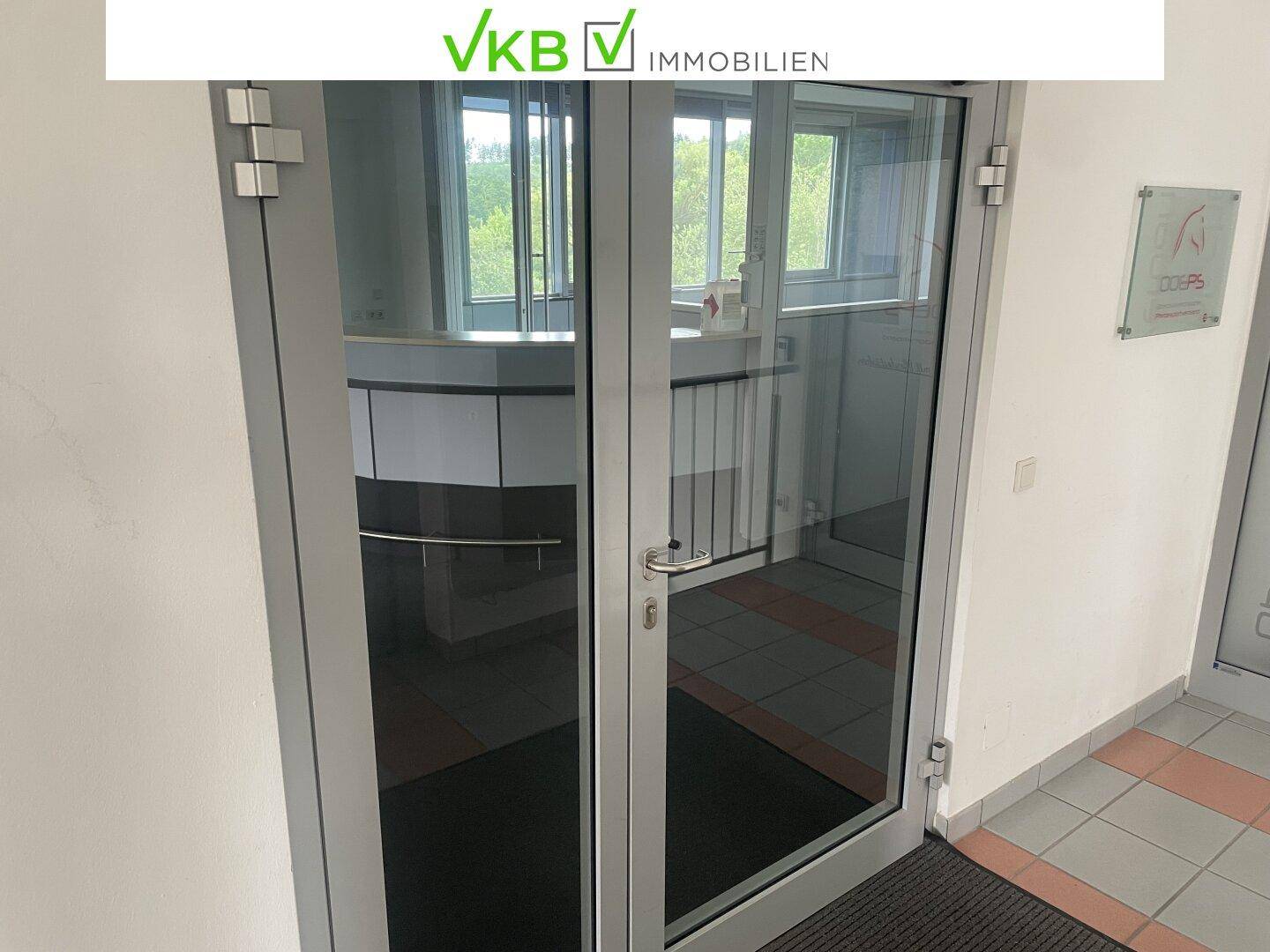 Glastür im Eingangsbereich, die den Blick auf einen weiteren Raum mit Fenstern freigibt.