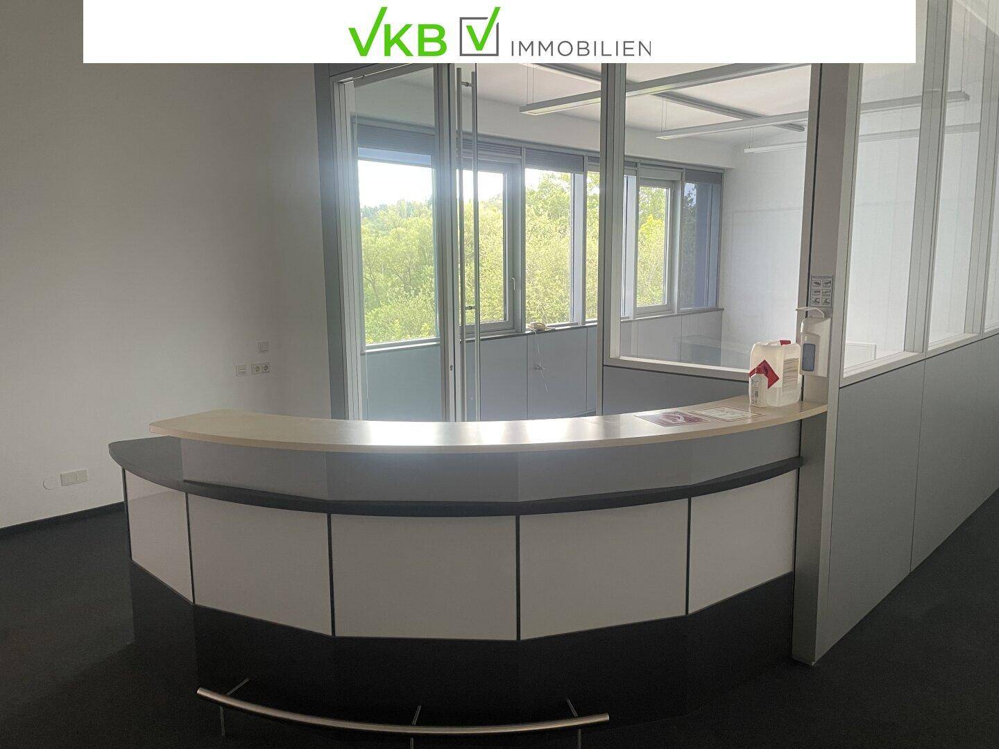 Empfangsbereich mit moderner Theke, Glaswänden und Blick auf die umliegende Landschaft.