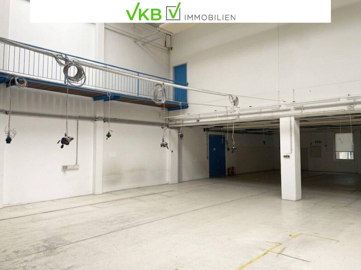Große Industriehalle mit erhöhter Plattform und Kabelinstallationen an der Decke.
