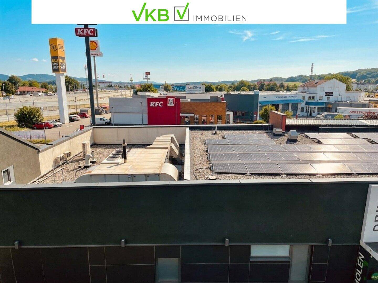 Dachansicht mit Photovoltaikanlage und Lüftungssystemen, umgeben von Gewerbegebäuden.