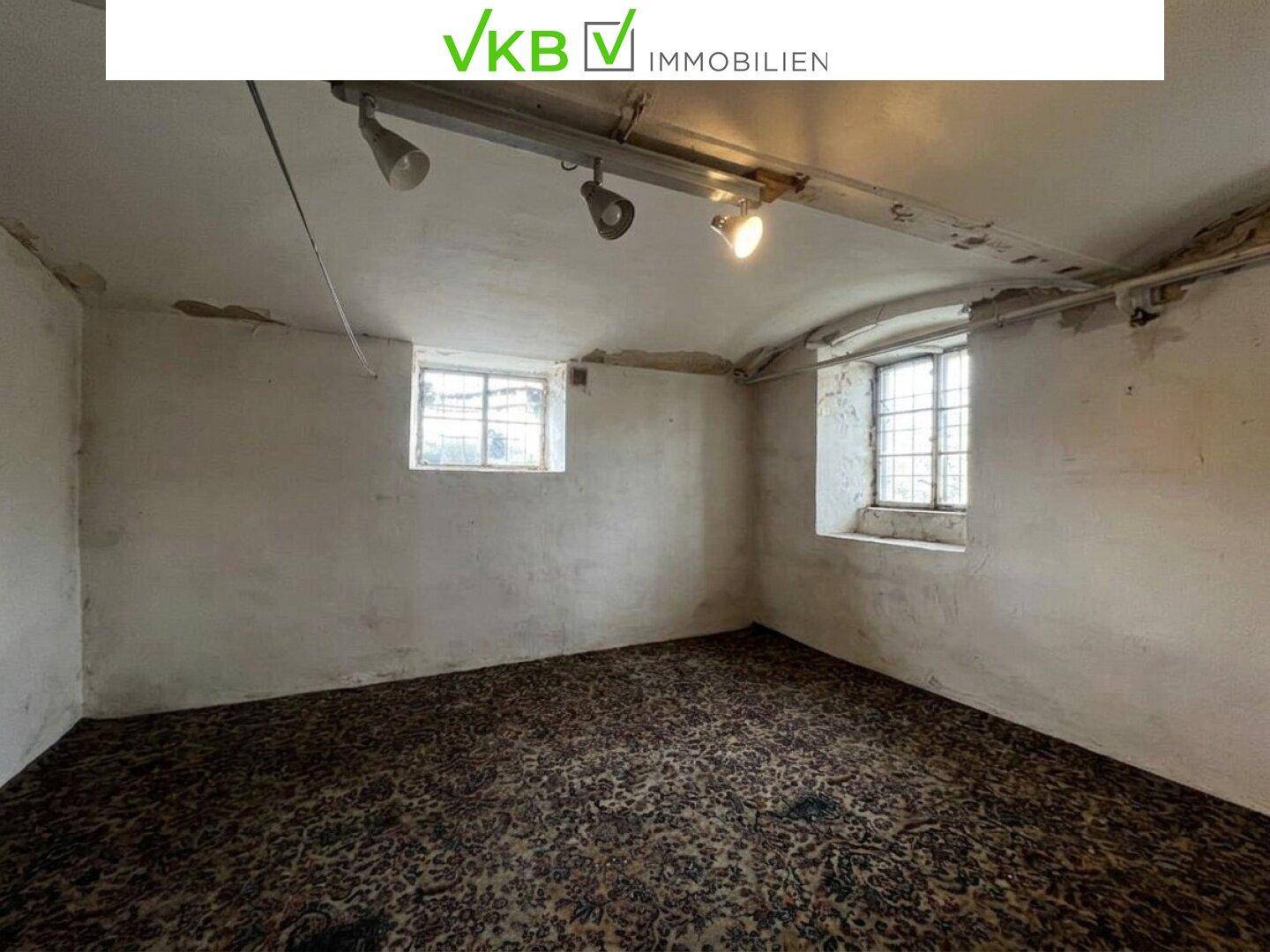 Leerer Raum mit rauen Wänden, Teppichboden und kleinen Fenstern.