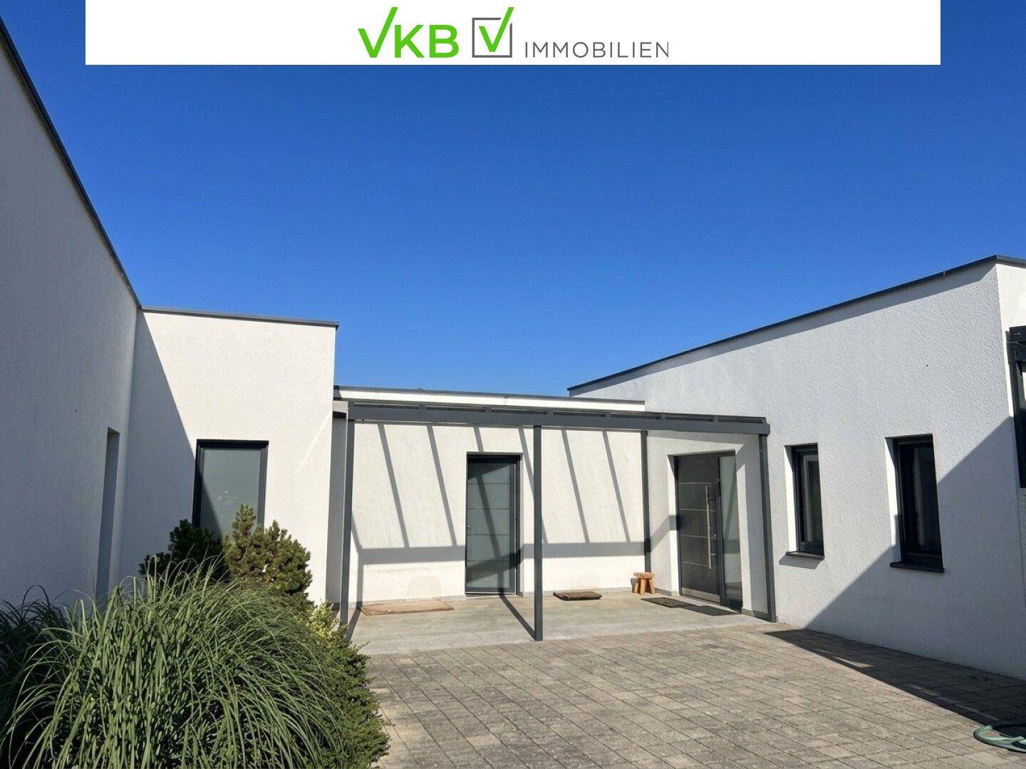 Klare Linien der modernen Hausfassade mit gepflastertem Zugang und überdachtem Bereich.