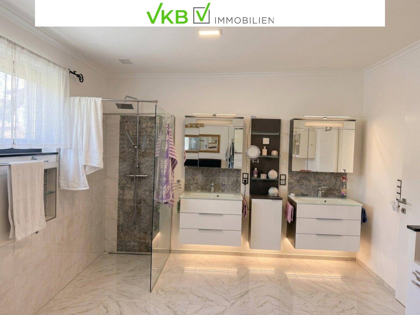 Modernes Badezimmer mit begehbarer Dusche, Doppelwaschbecken und großen Fliesen.