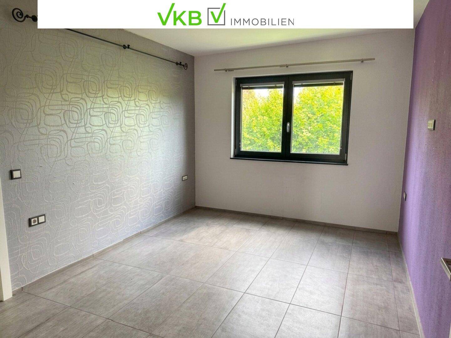 Geräumiges Zimmer mit Fliesenboden, Fenster und farbigen Wänden, bereit zur Einrichtung.