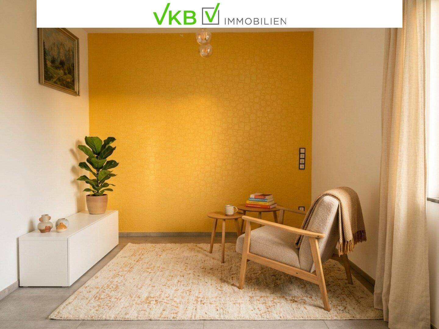 Heller Sitzbereich mit Sessel, Beistelltisch und einer auffälligen gelben Akzentwand.