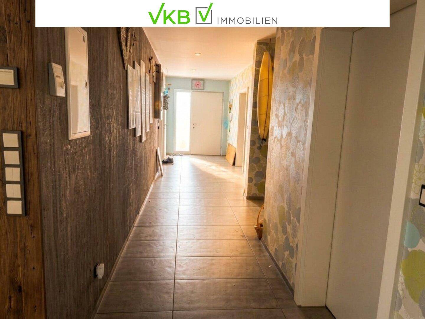 Langer Flur mit Fliesenboden, Holzakzentwand und dekorativer Tapete.