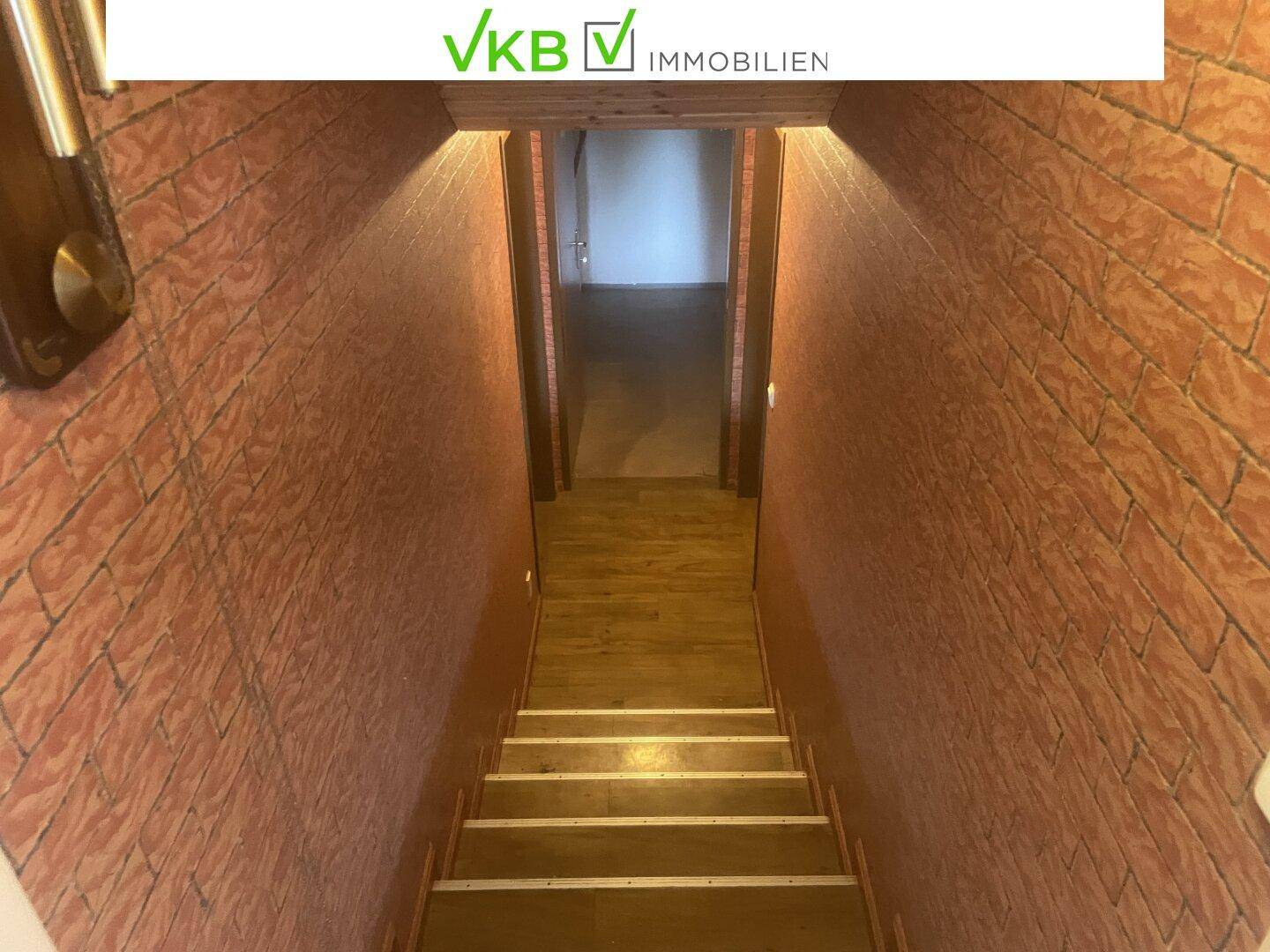 Treppenabgang zum Keller mit Holzstufen und Wänden in Ziegelsteinoptik.