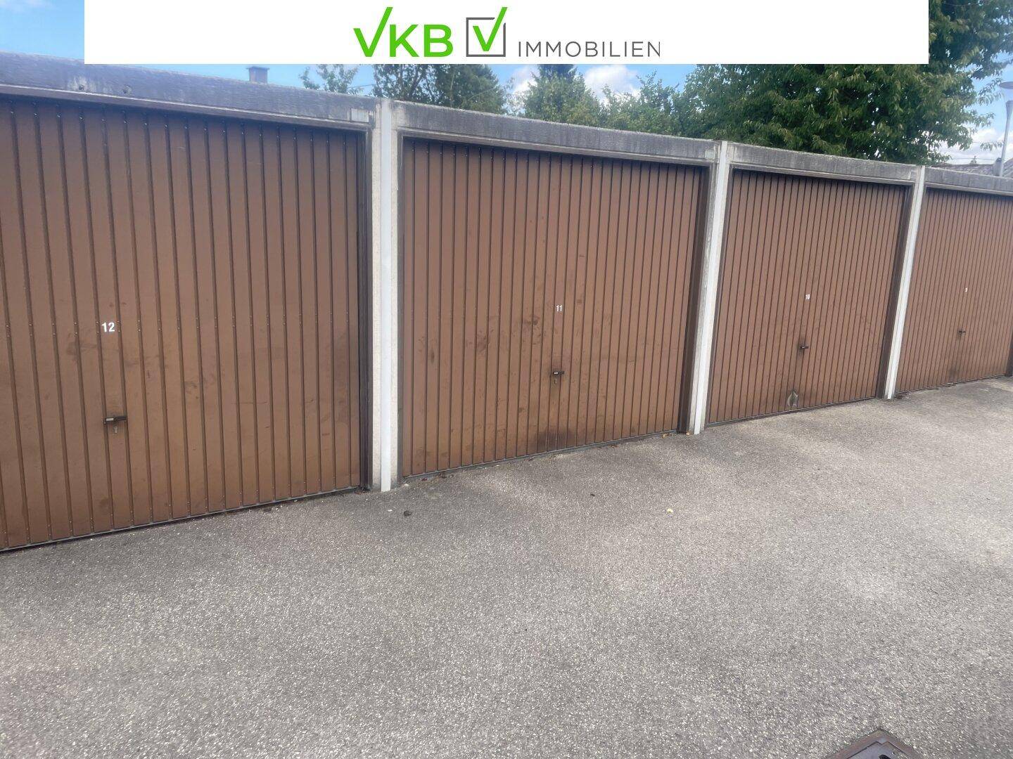 Reihe von Garagen mit braunen Holztoren und asphaltiertem Vorplatz.