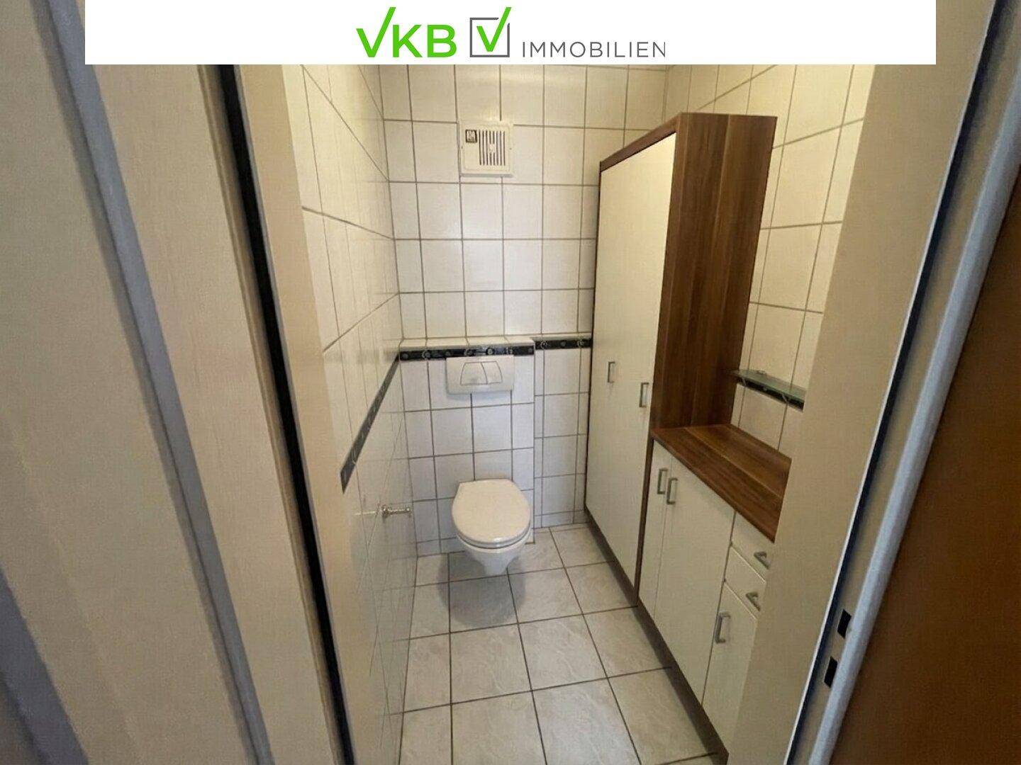 Kleines Gäste-WC mit weißen Fliesen, Wand-WC und praktischen Einbauschränken.