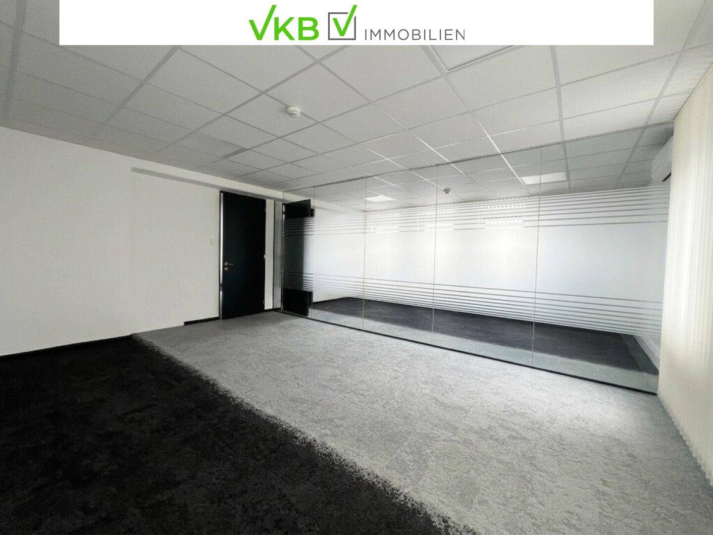 Modernes Büro mit Teppichboden, Glaswand und abgehängter Decke, ideal für flexible Arbeitsbereiche.