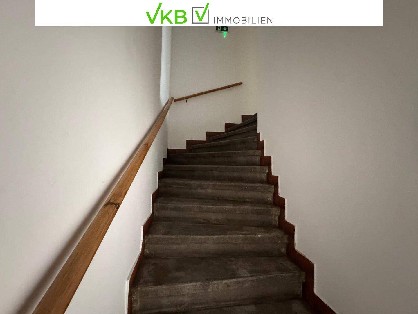 Treppenhaus mit Holzgeländer und robusten Stufen, das die Stockwerke miteinander verbindet.