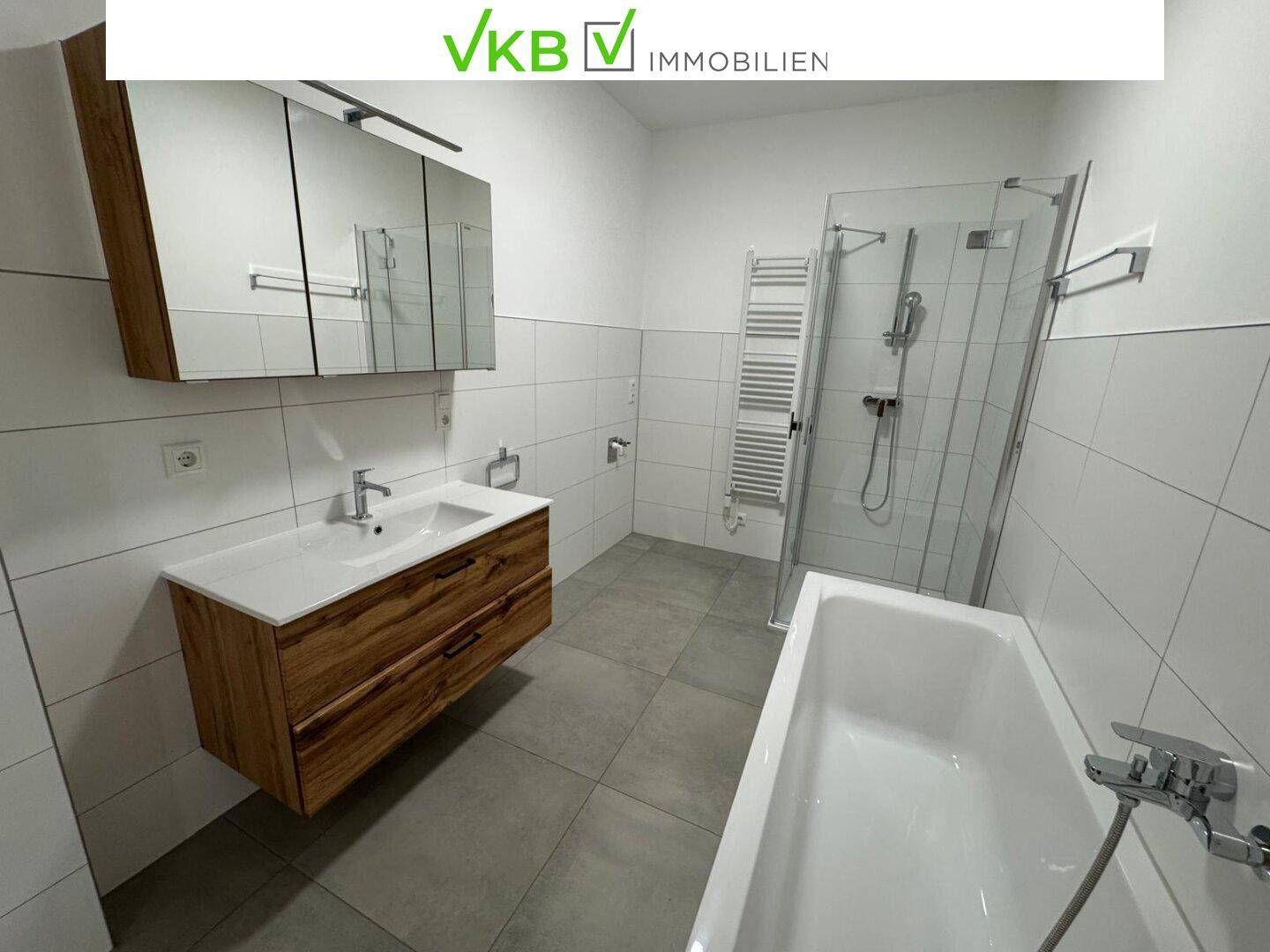 Modernes Badezimmer mit Badewanne, Duschkabine und einem stilvollen Holzwaschtisch.