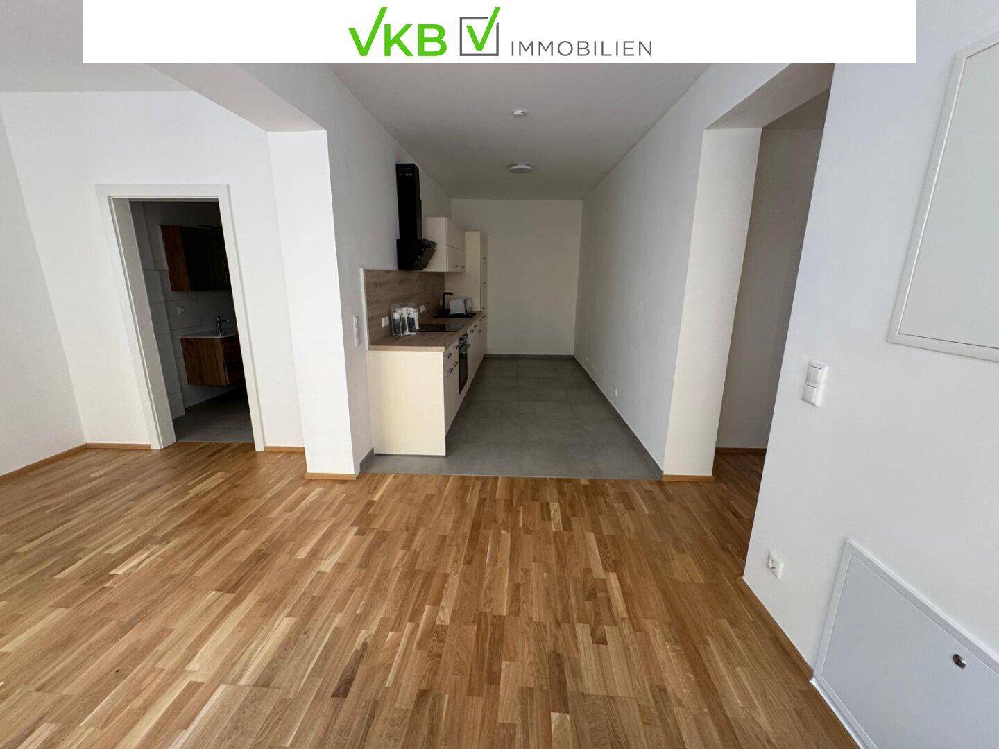 Heller Wohnbereich mit Holzboden und offener Küchenzeile, bereit für die individuelle Gestaltung.