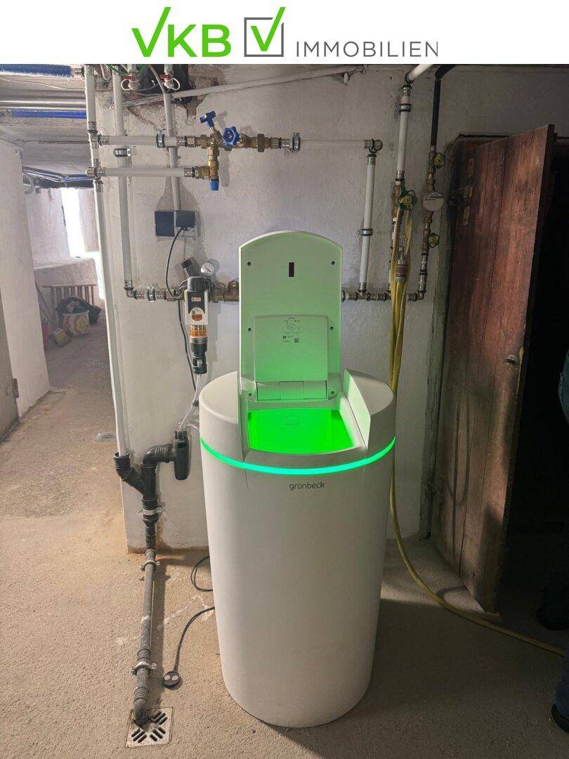 Moderne Wasseraufbereitungsanlage von Grünbeck mit leuchtender Anzeige in einem Technikraum im Keller.
