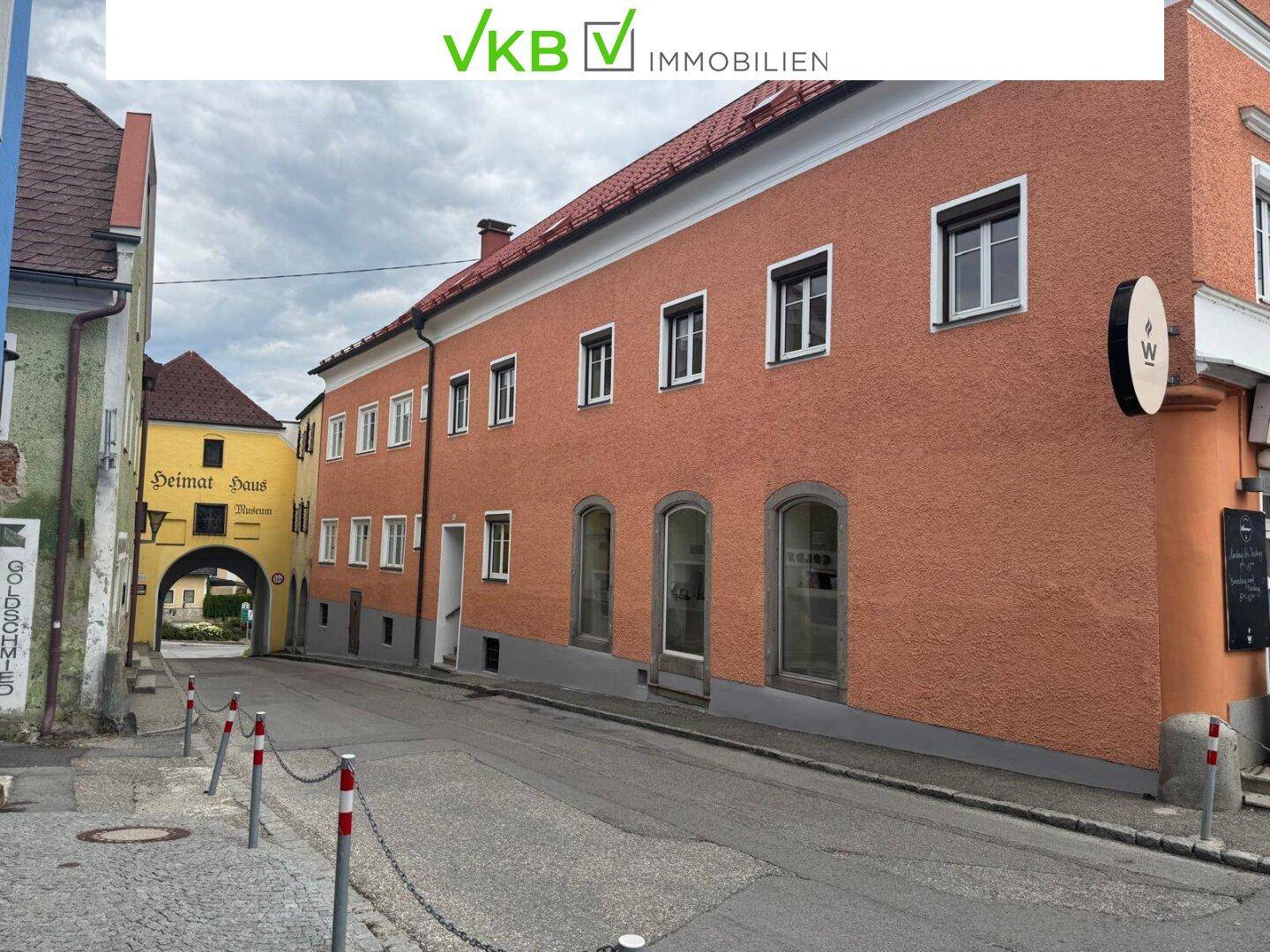 Historisches Gebäude mit orangeroter Fassade an einer engen Gasse in einer europäischen Altstadt.