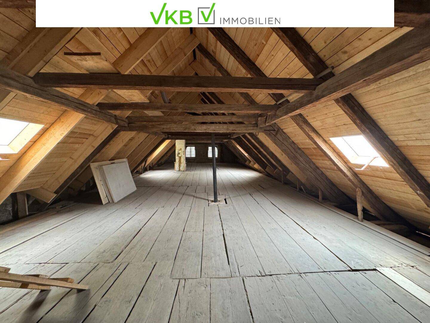 Geräumiger Dachboden mit sichtbaren Holzbalken und Dachfenstern, bereit für einen möglichen Ausbau.
