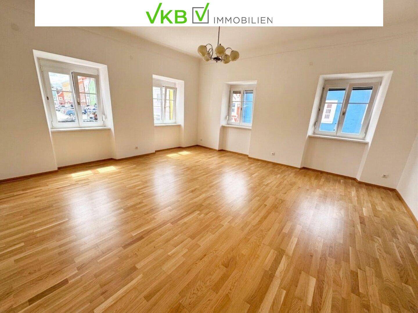 Heller Wohnraum mit Parkettboden und mehreren Fenstern, die einen weiten Blick bieten.