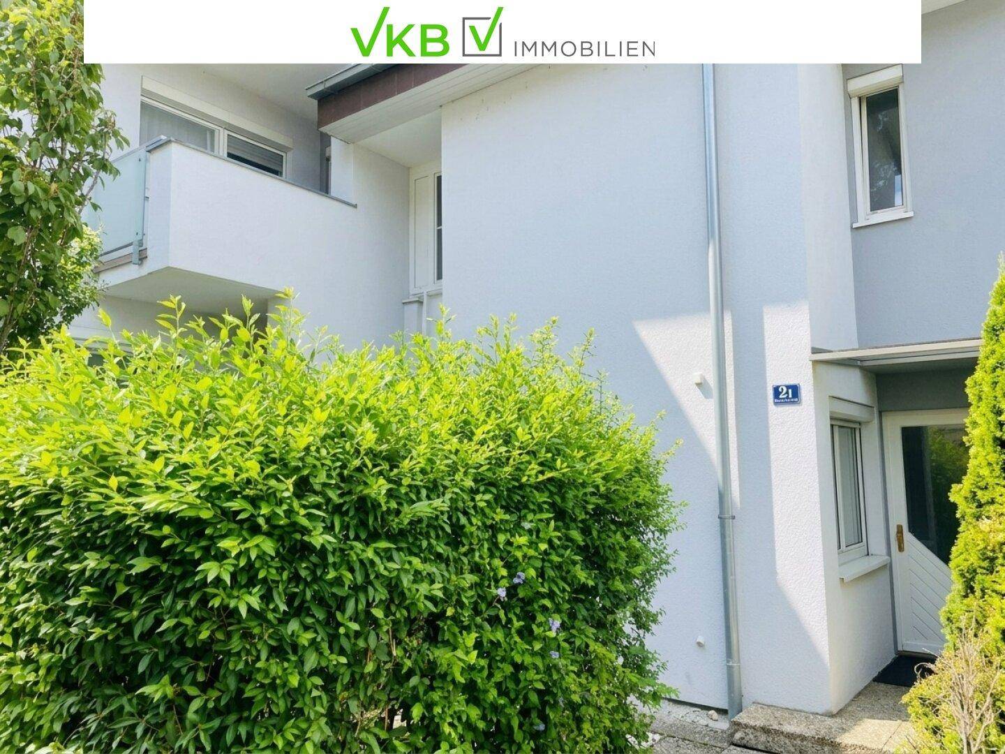 Moderne Gebäudefassade mit großen Fenstern und einem gepflegten Vorgartenbereich.