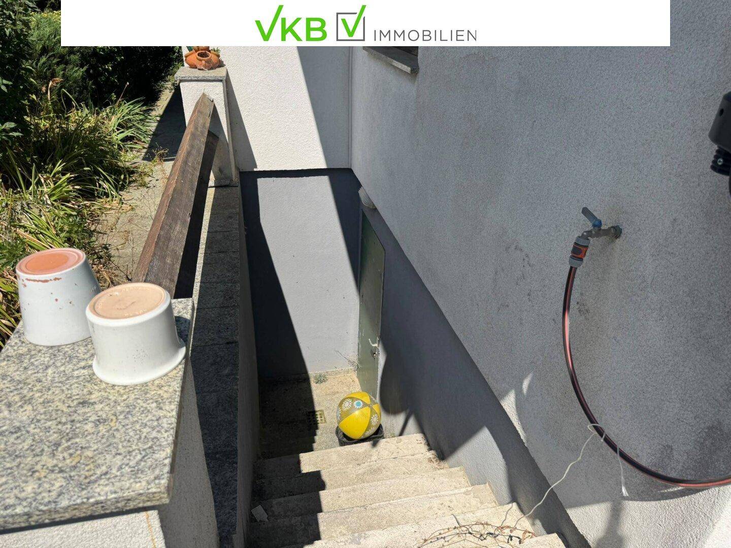Außentreppe führt zum Kellereingang, ausgestattet mit einem Wasserhahn und Gartenschlauch.