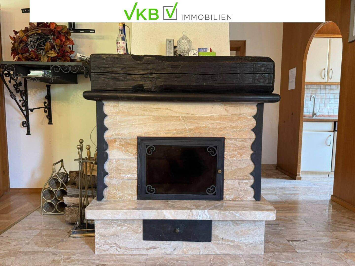 Rustikaler Kamin mit Marmorverkleidung und Holzscheitablage, ein Blickfang im Wohnbereich.