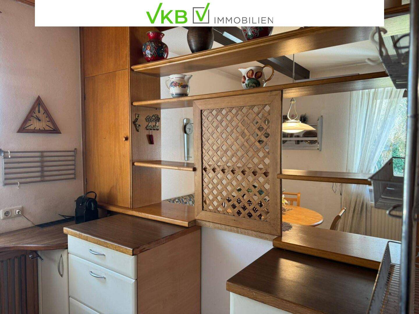Traditionelle Küche mit Holzschränken und einer Durchreiche zum Essbereich, funktional eingerichtet.
