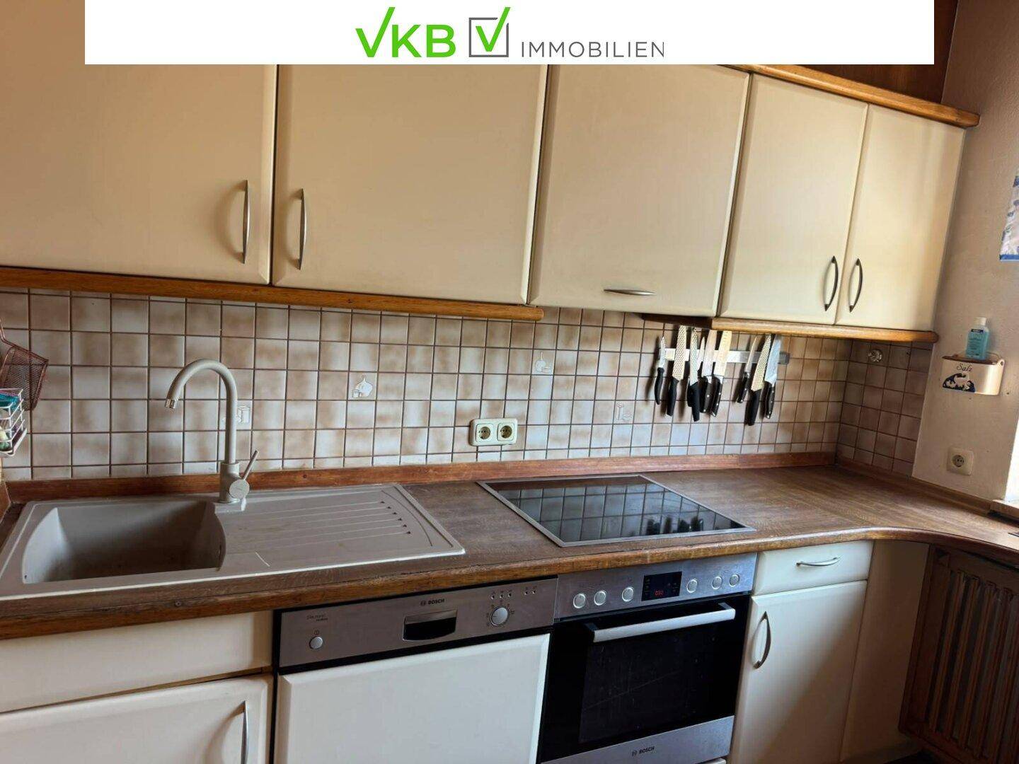 Funktionale Küche mit beigen Schränken, Spülmaschine und Kochfeld, bereit zur Nutzung.