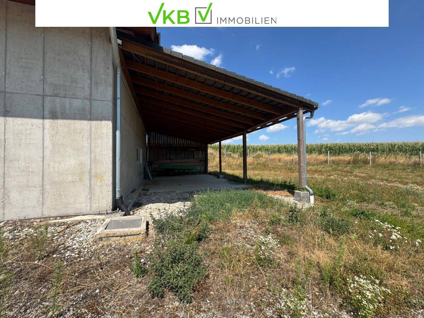 Überdachter Außenbereich mit Holzkonstruktion, angrenzend an die Scheune, ideal als Unterstand.