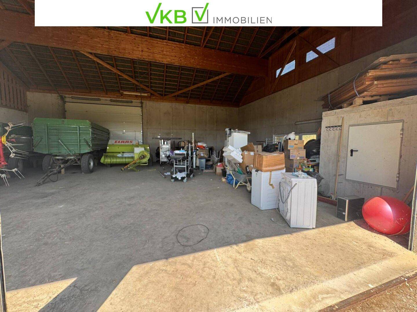 Innenansicht der großen Scheune mit vielfältigen Lagergegenständen und landwirtschaftlichen Maschinen.