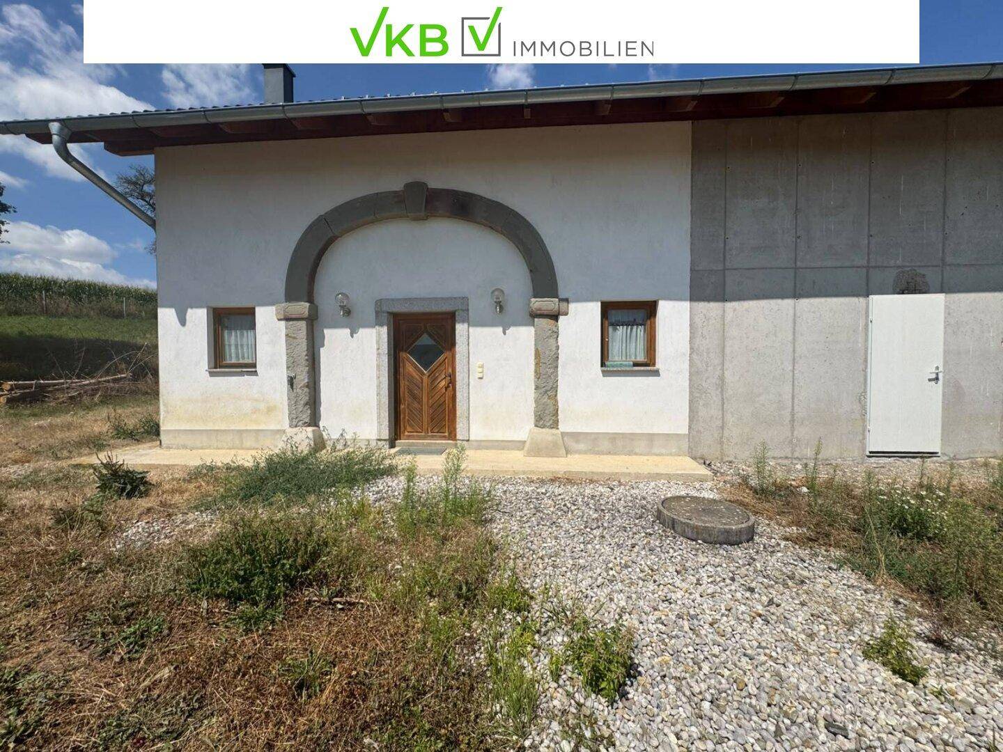 Fassade des Gebäudes mit einem markanten steinernen Bogenportal und kleinen Fenstern.