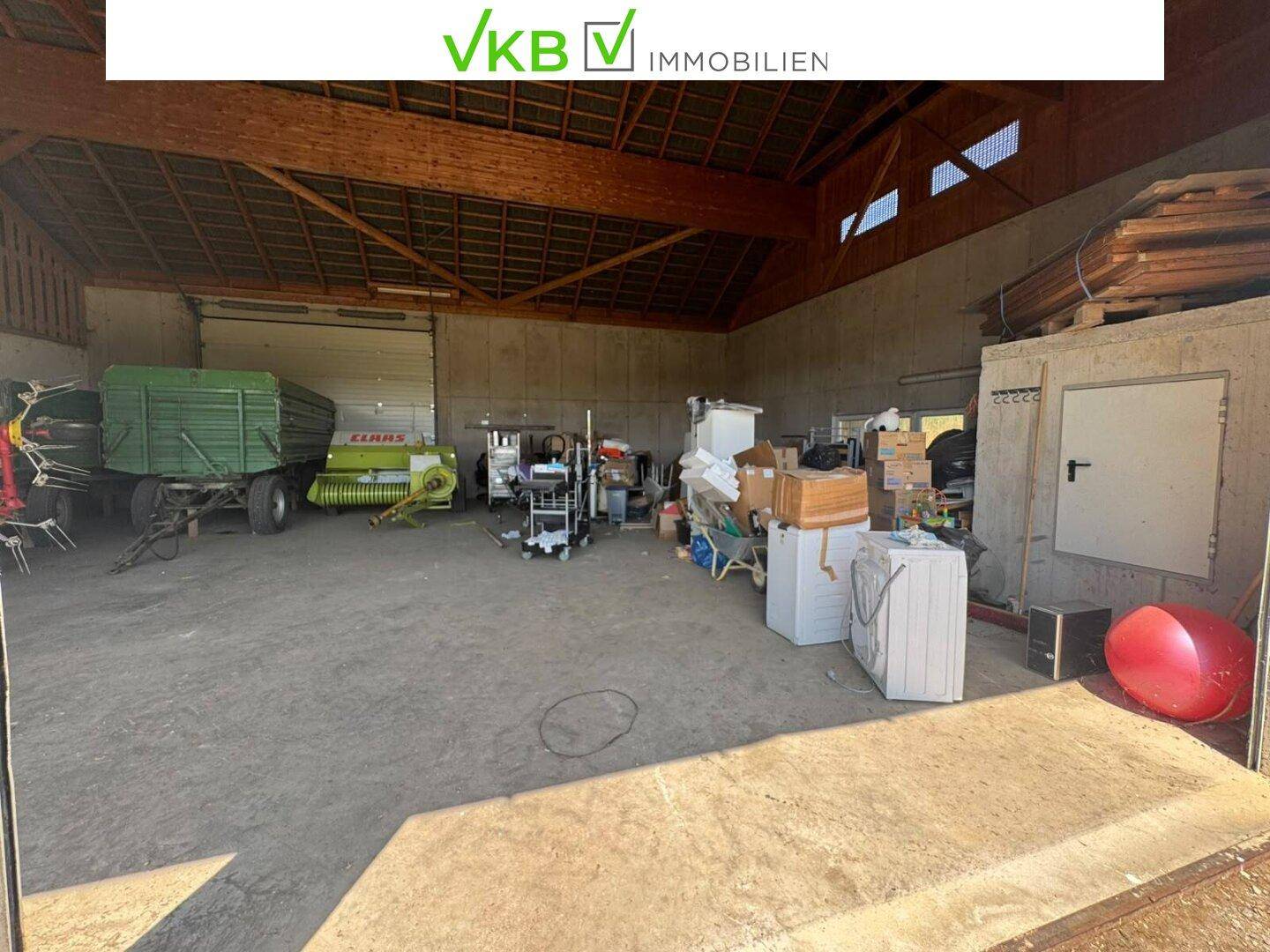 Innenansicht der großen Scheune mit vielfältigen Lagergegenständen und landwirtschaftlichen Maschinen.