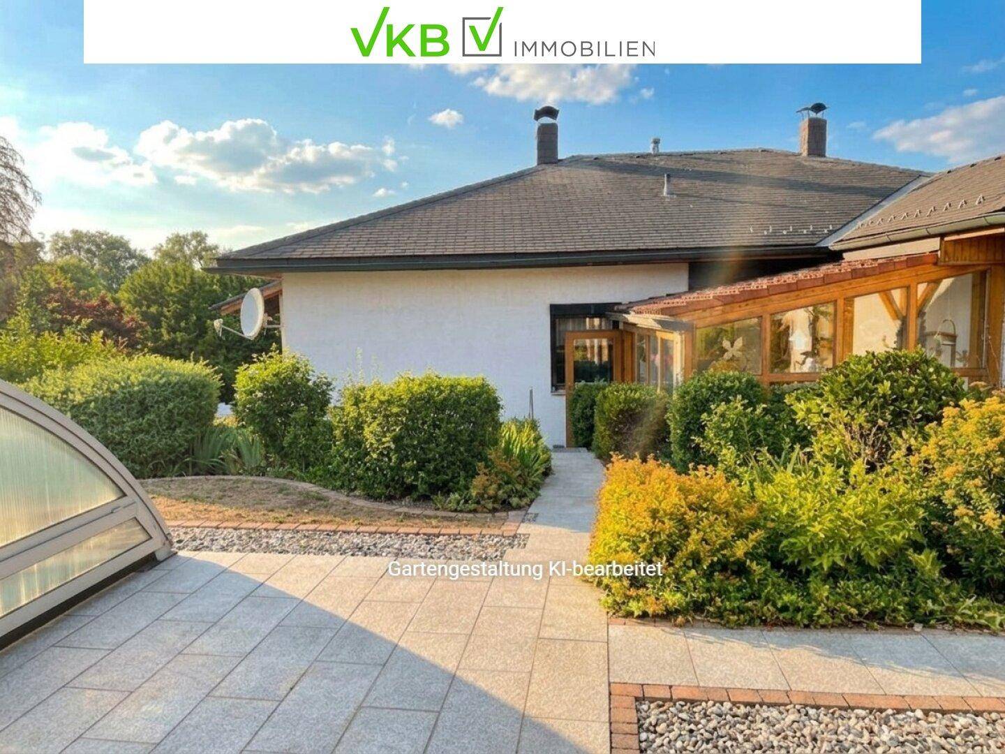 Seitenansicht des Hauses mit gepflastertem Bereich, Hecken und einem Wintergarten unter strahlendem Sonnenschein.