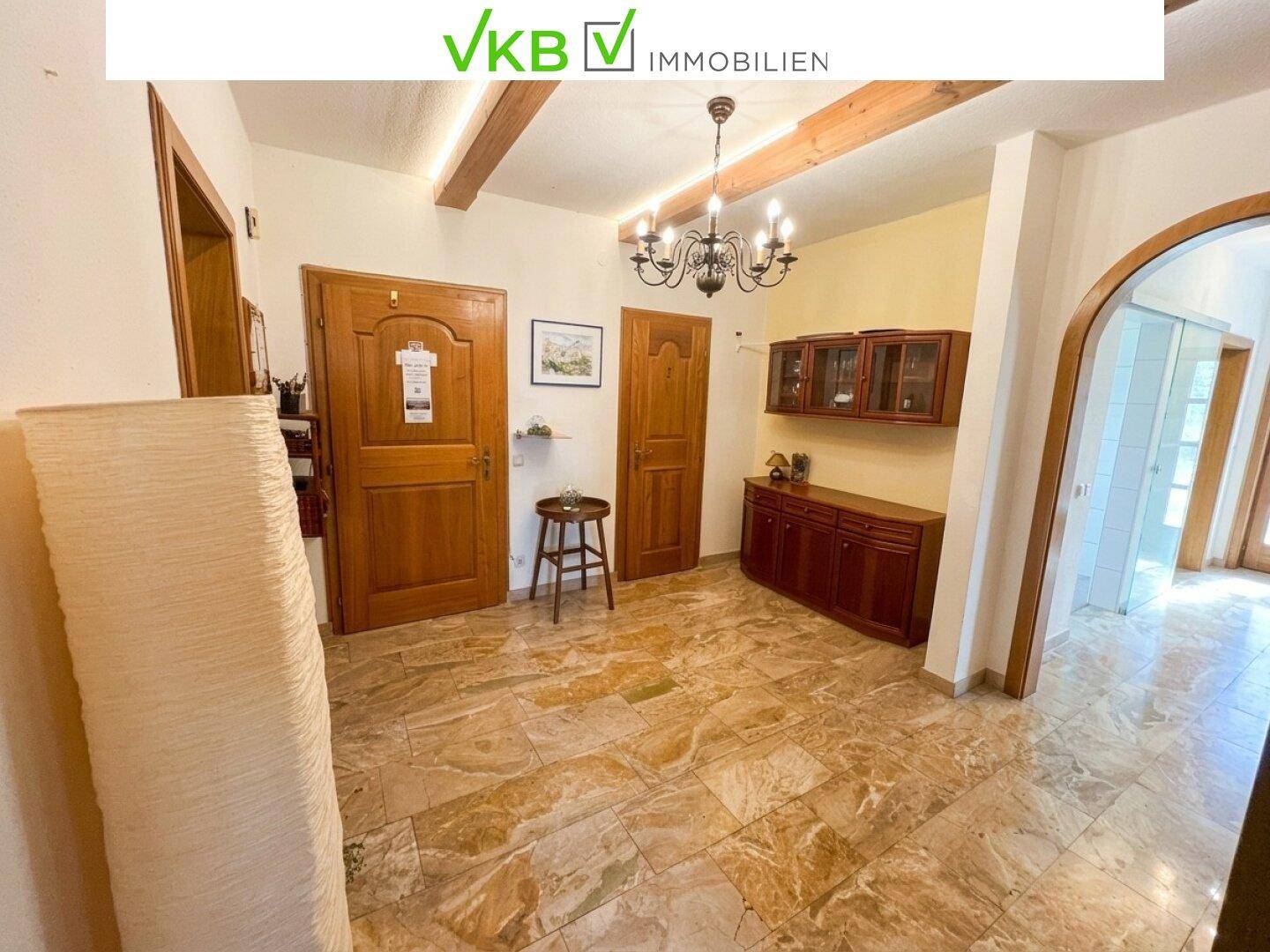 Geräumiger Flur mit gefliestem Boden, Holzbalken an der Decke und traditionellen Holzmöbeln.