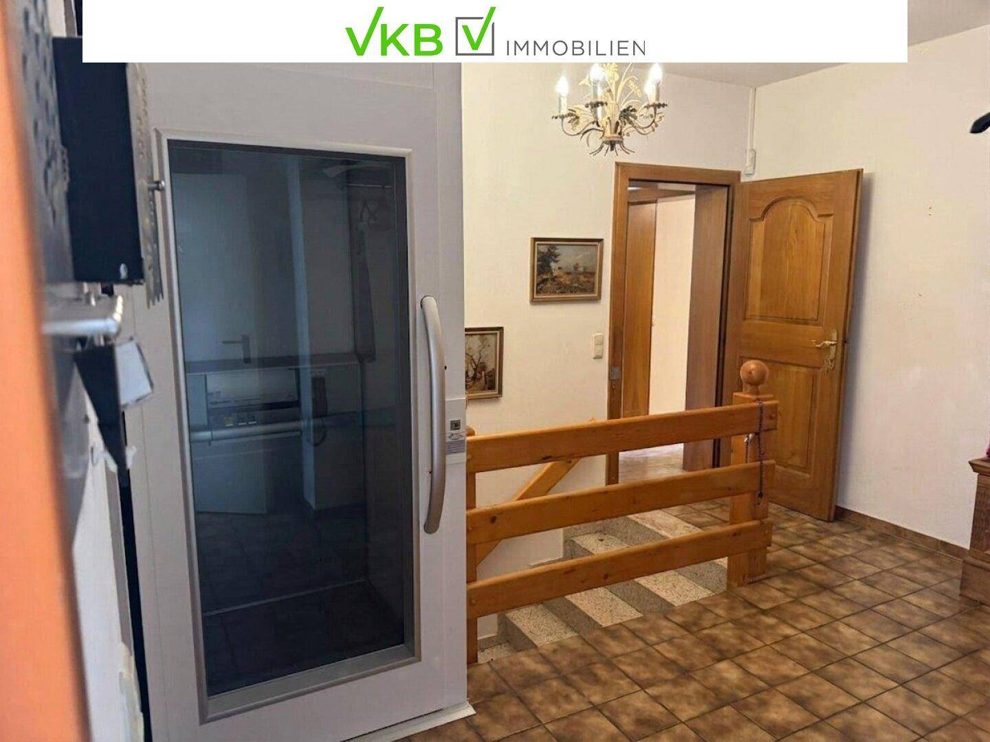 Flur mit Aufzug und Holztreppe, der den Zugang zu verschiedenen Ebenen des Hauses ermöglicht.