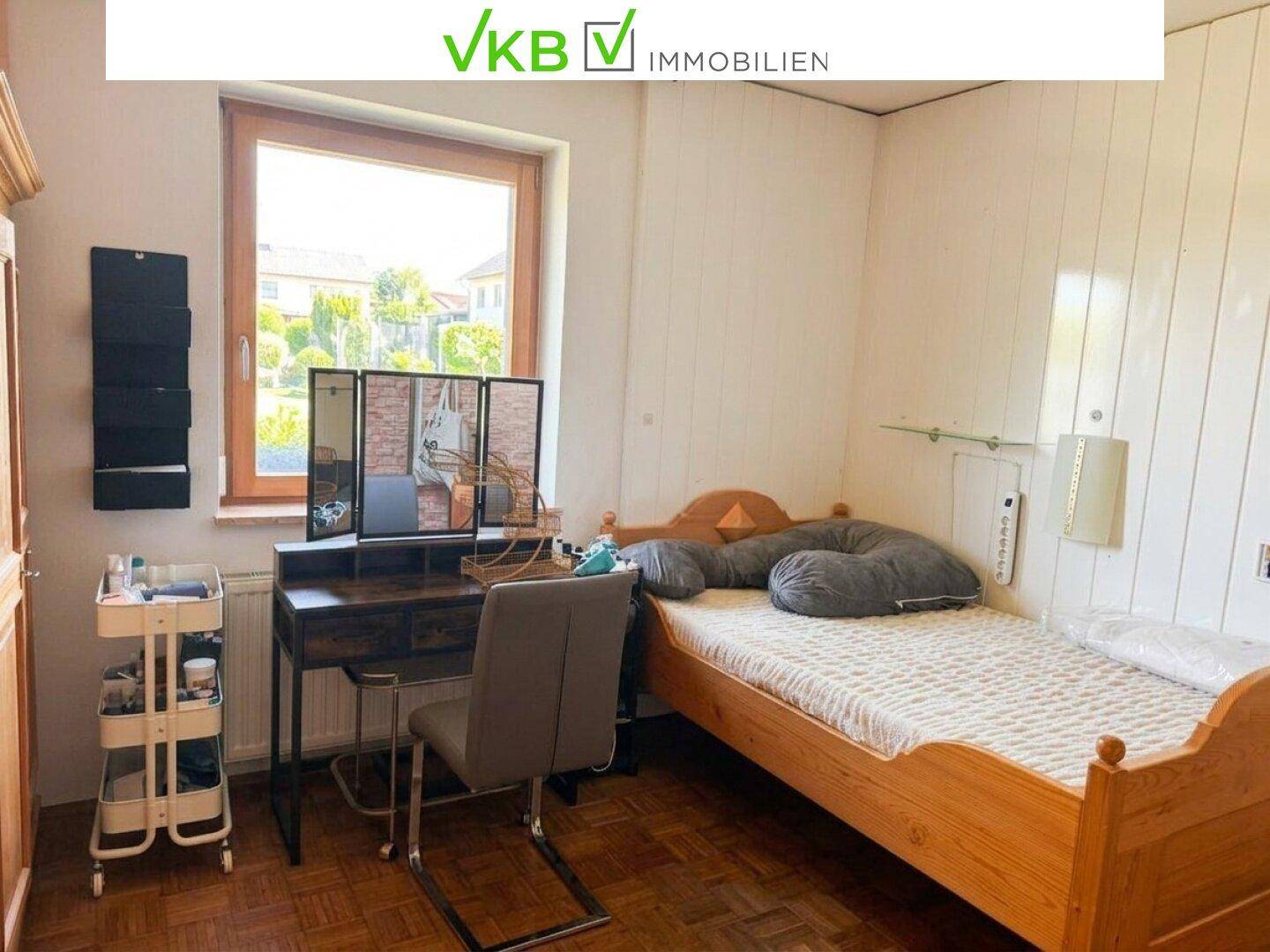 Schlafzimmer mit Einzelbett, Schreibtisch und Fenster, bietet einen ruhigen Rückzugsort.