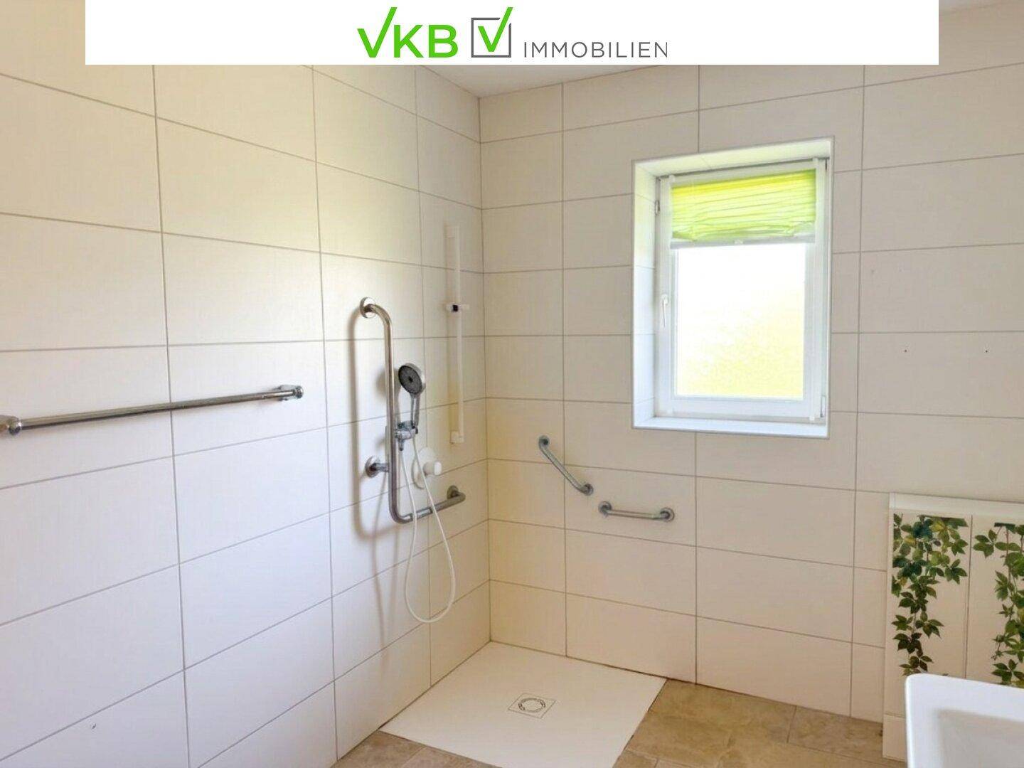 Barrierefreie Dusche im Badezimmer mit Haltegriffen und Fenster, bietet Komfort und Sicherheit.