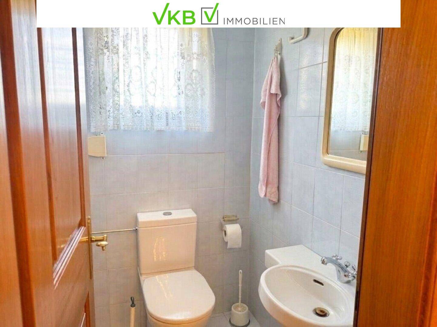 Kleines Gäste-WC mit Waschbecken und Toilette, praktisch und hell durch das Fenster.