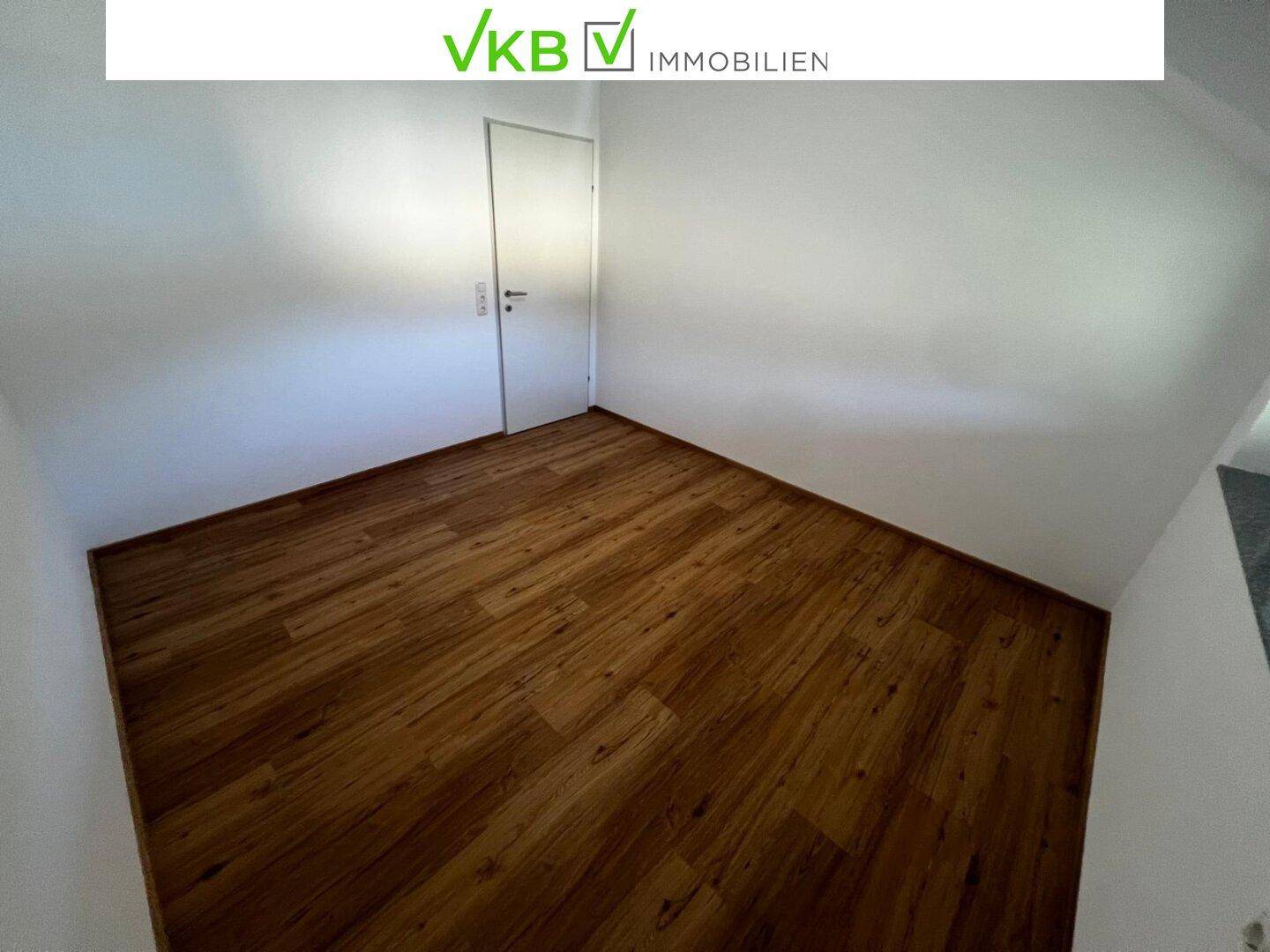 Leeres Schlafzimmer mit Laminatboden und weiß gestrichenen Wänden.