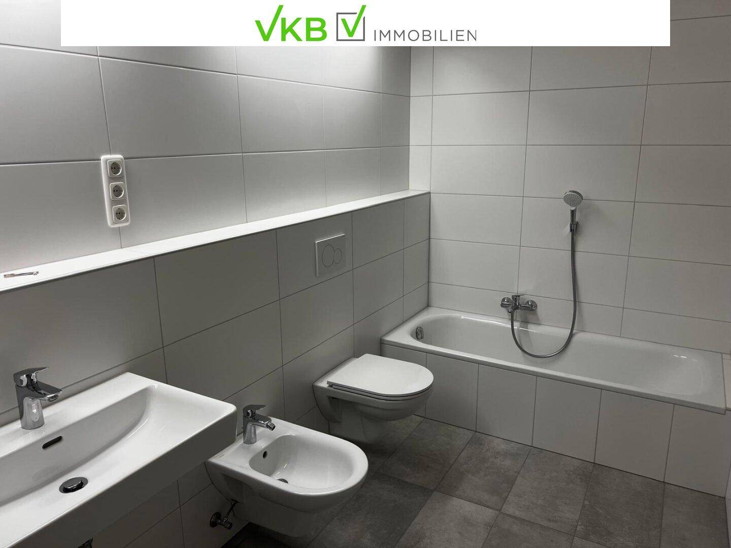 Modernes Badezimmer mit Badewanne, Bidet, Doppelwaschbecken und hellen Fliesen.