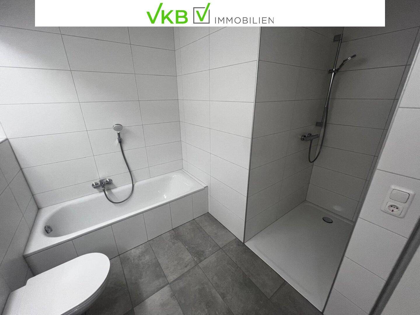 Modernes Badezimmer mit Badewanne, ebenerdiger Dusche und hellen Fliesen.