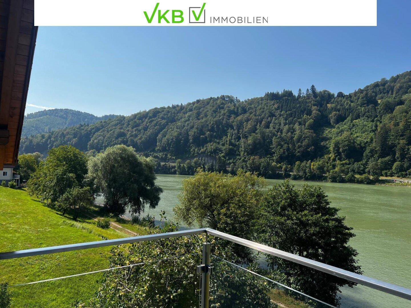 Balkon mit Glasgeländer bietet einen malerischen Blick auf den Fluss und die grüne Landschaft.