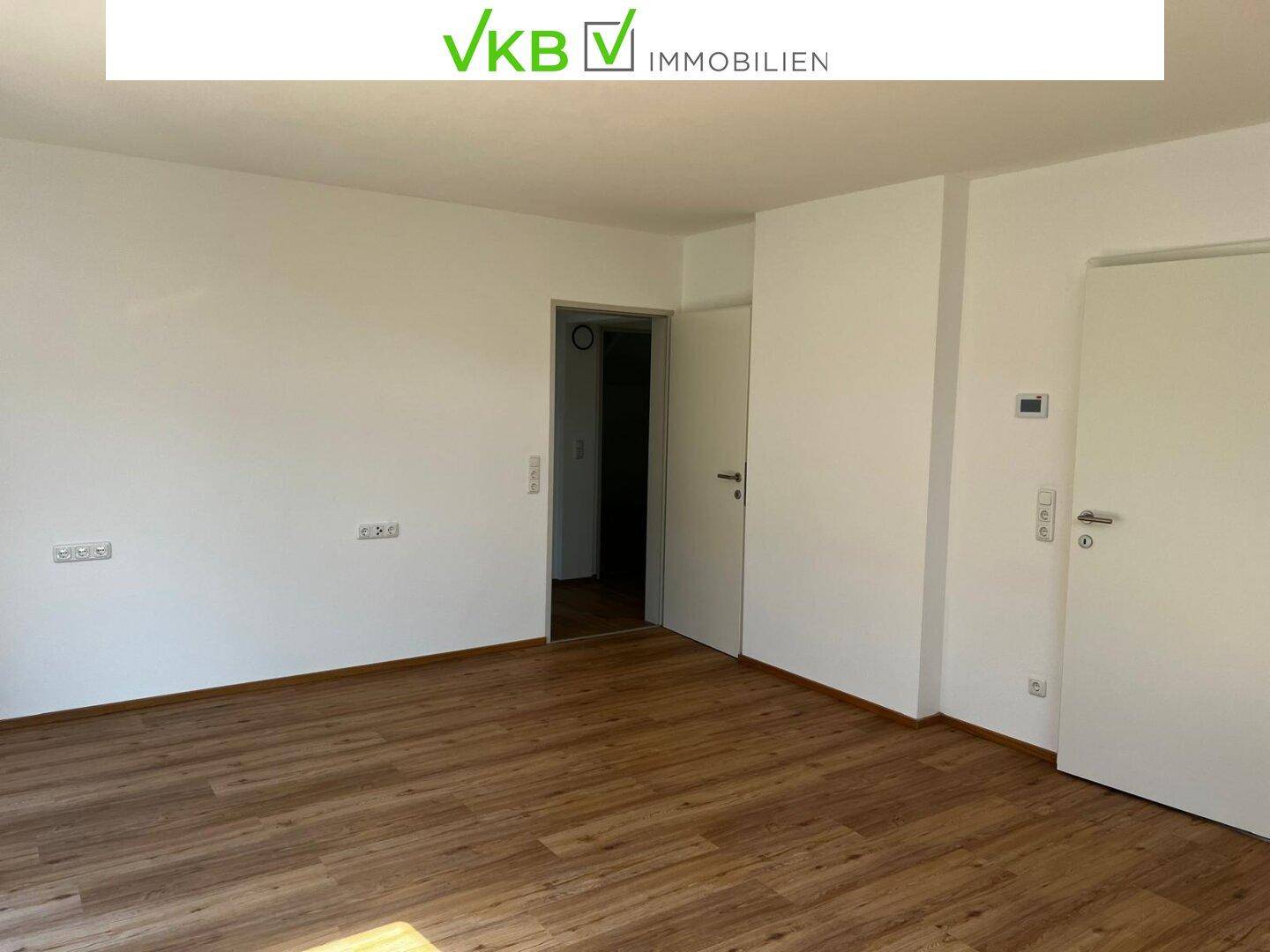 Heller, leerer Raum mit Laminatboden und weiß gestrichenen Wänden.