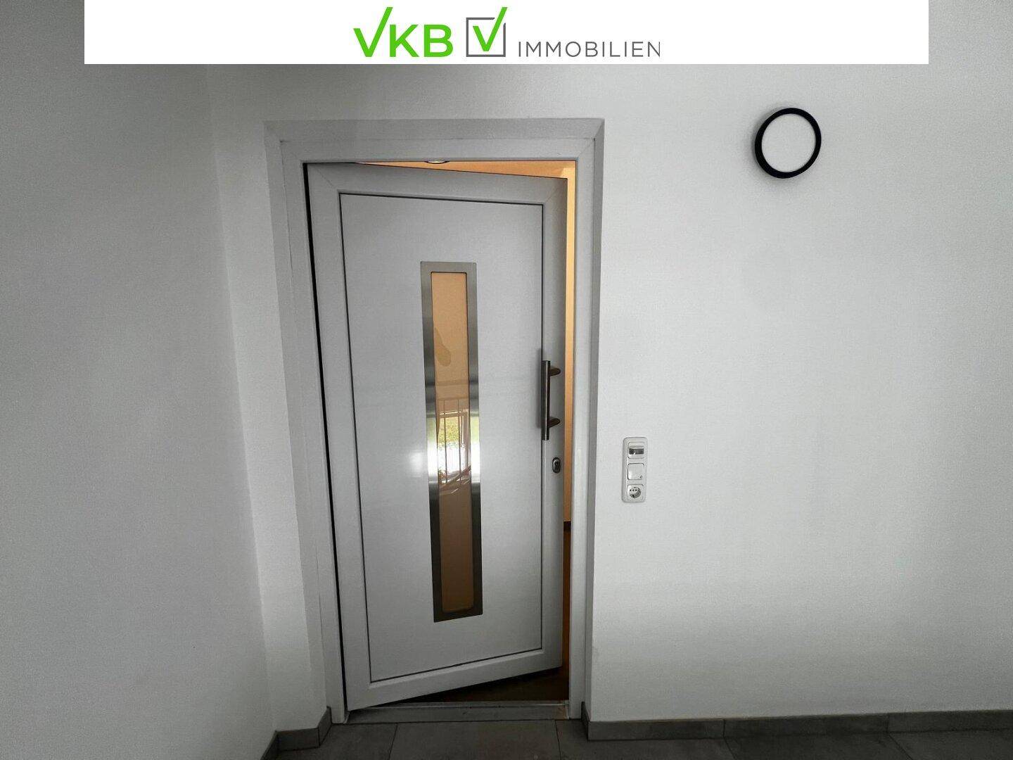 Moderne weiße Eingangstür mit Glaseinsatz in einem hellen Flurbereich.