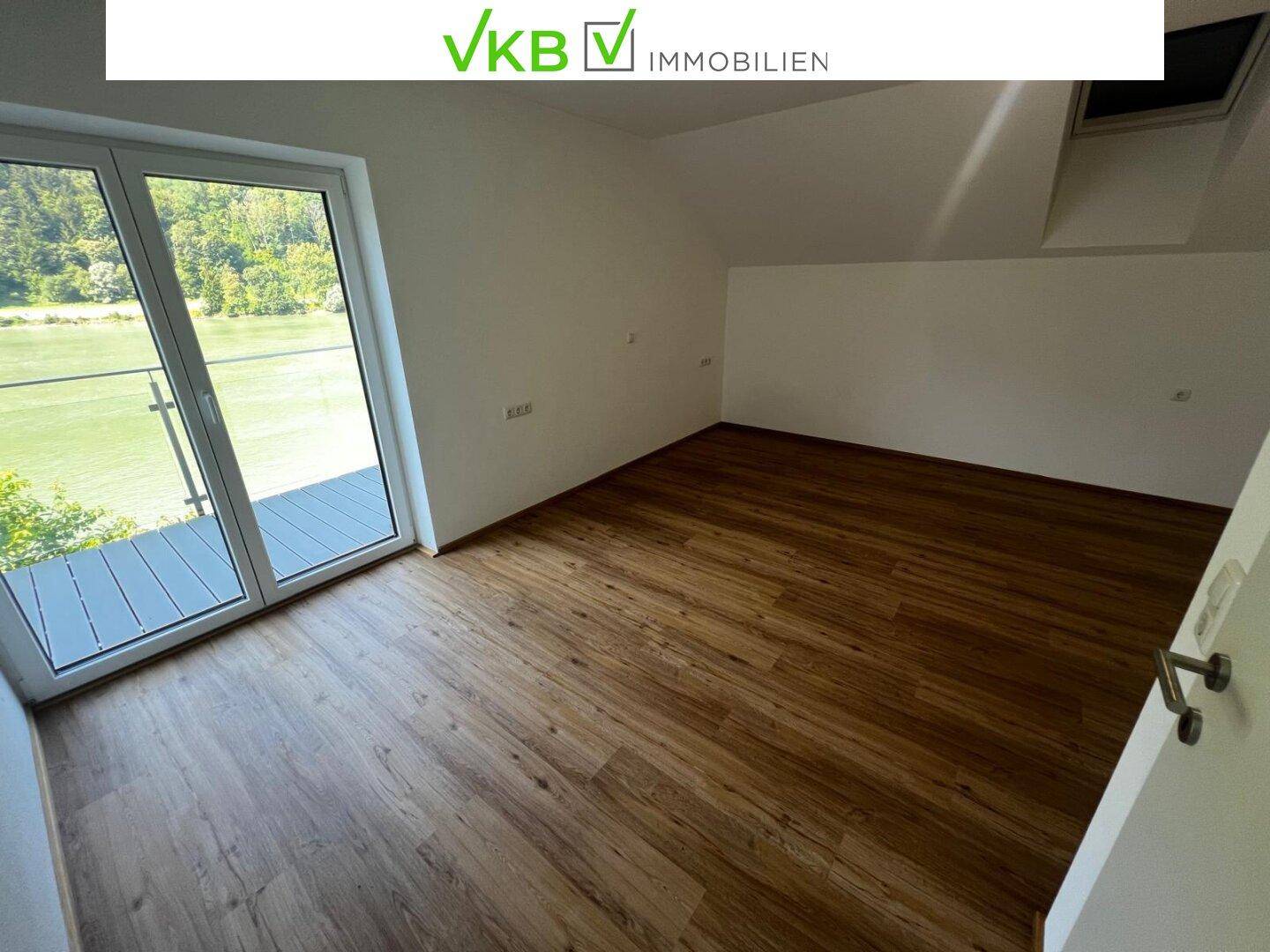 Helles Schlafzimmer mit Balkonzugang, Laminatboden und Dachfenster.