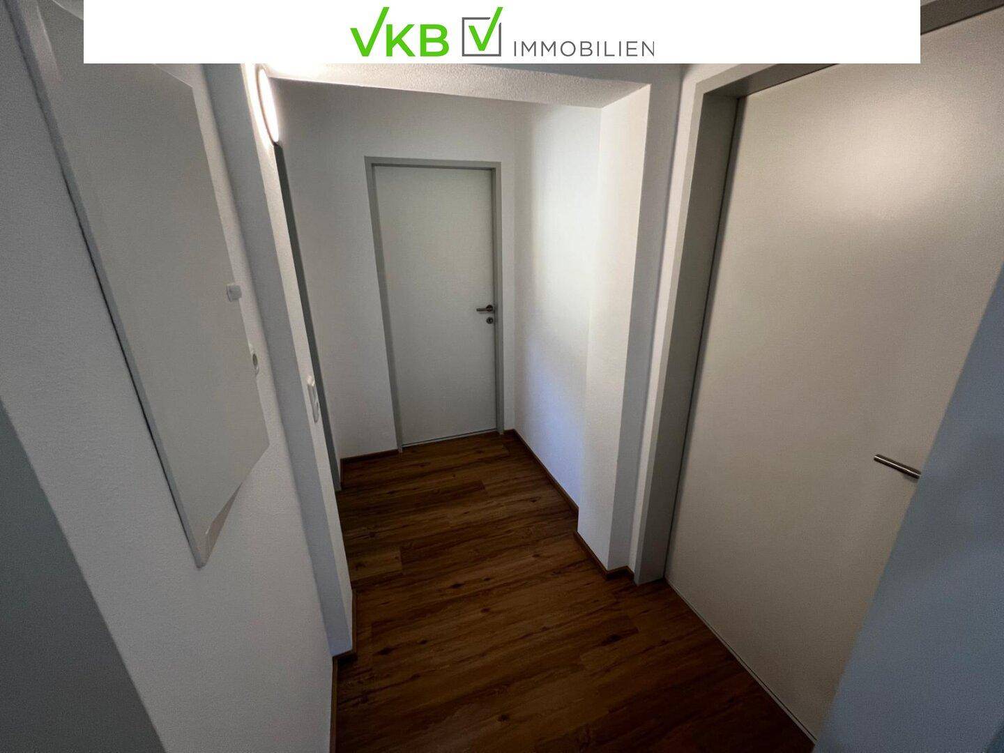 Heller Flur mit Holz-Laminatboden und modernen Wandleuchten.
