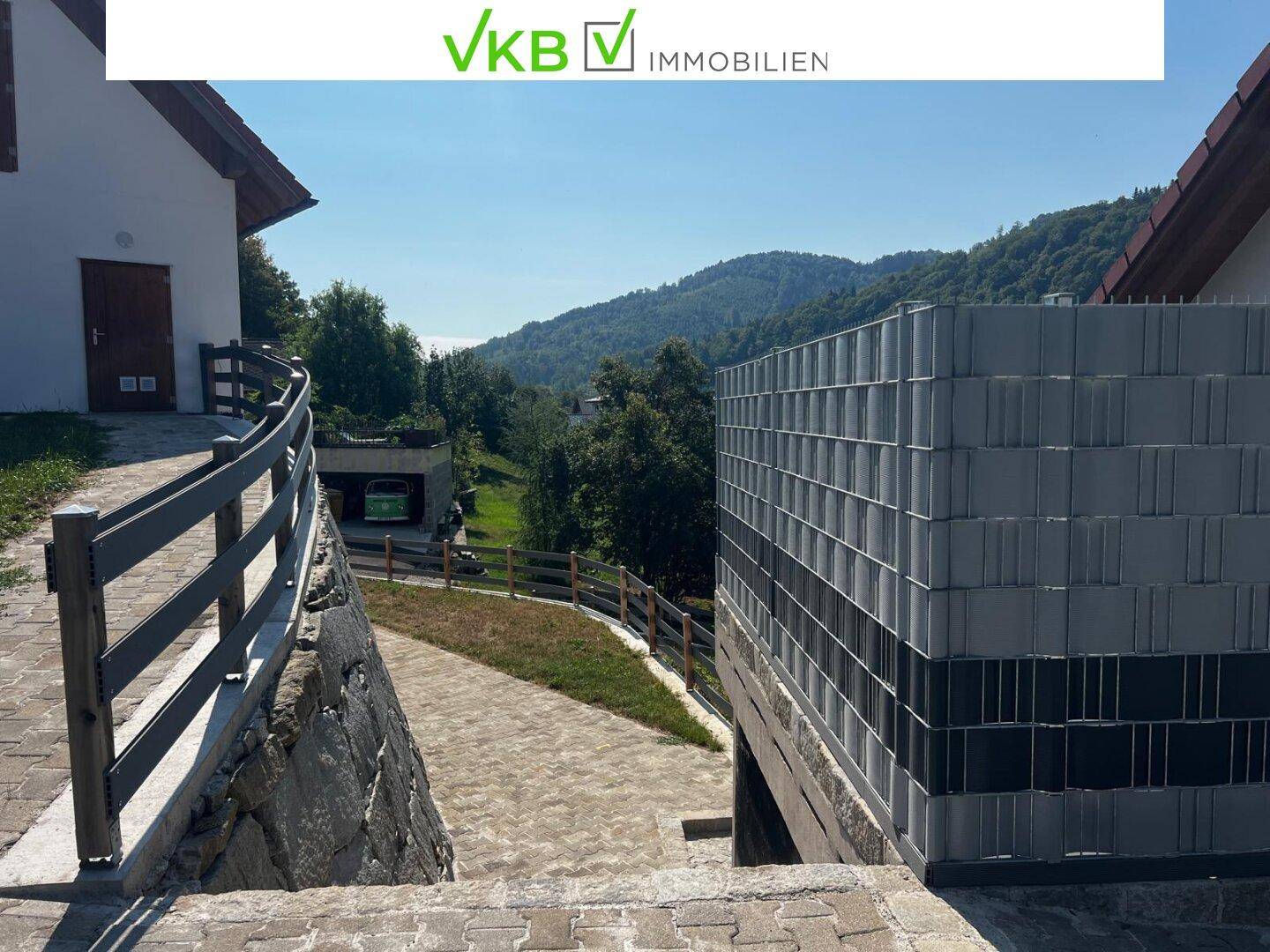 Gepflasterter Weg führt zum Haus mit Blick auf die grüne Hügellandschaft.