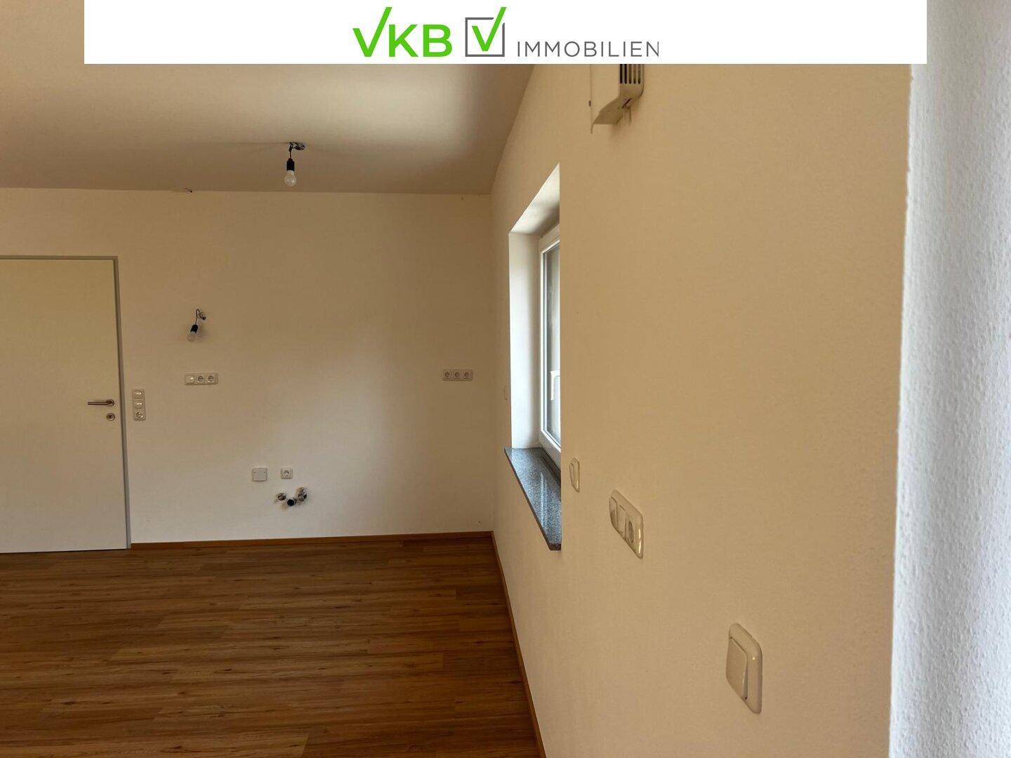 Heller, leerer Raum mit Laminatboden, weißen Wänden und einem Fenster.
