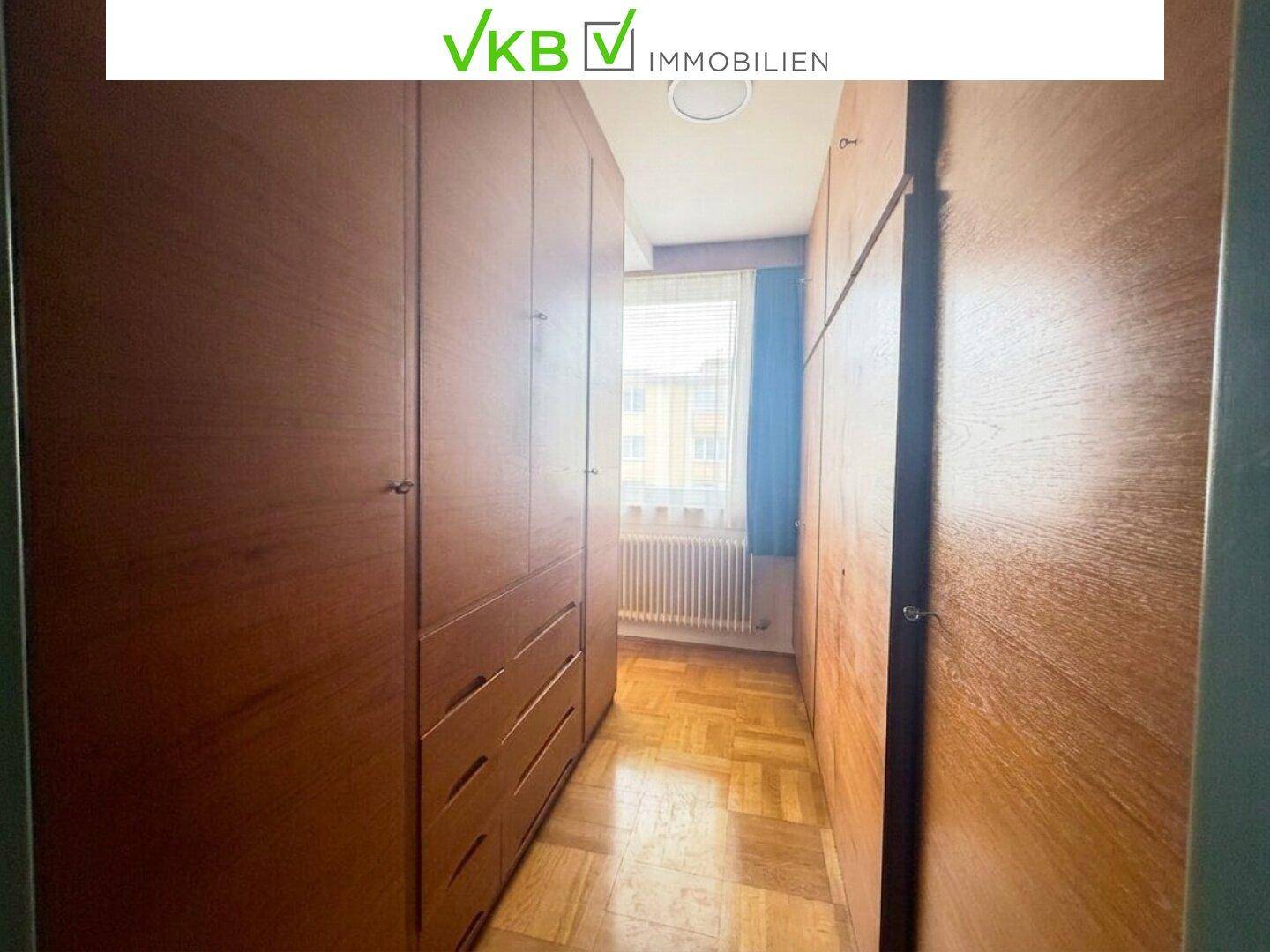 Begehbarer Kleiderschrank mit vielen Holzschränken und Parkettboden, der viel Stauraum bietet.