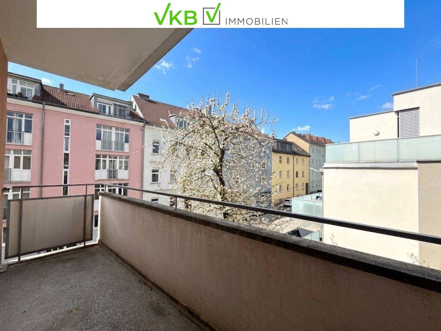 Balkon mit Blick auf die farbenfrohen Gebäude der Nachbarschaft und einen blühenden Baum.